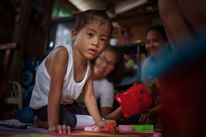 Ein kleiner Junge krabbelt auf dem Boden in einer Hütte, im Hintergrund sitzen zwei Frauen (Quelle: Jakob Studnar) Ein kleiner Junge krabbelt auf dem Boden in einer Hütte, im Hintergrund sitzen zwei Frauen (Quelle: Jakob Studnar)