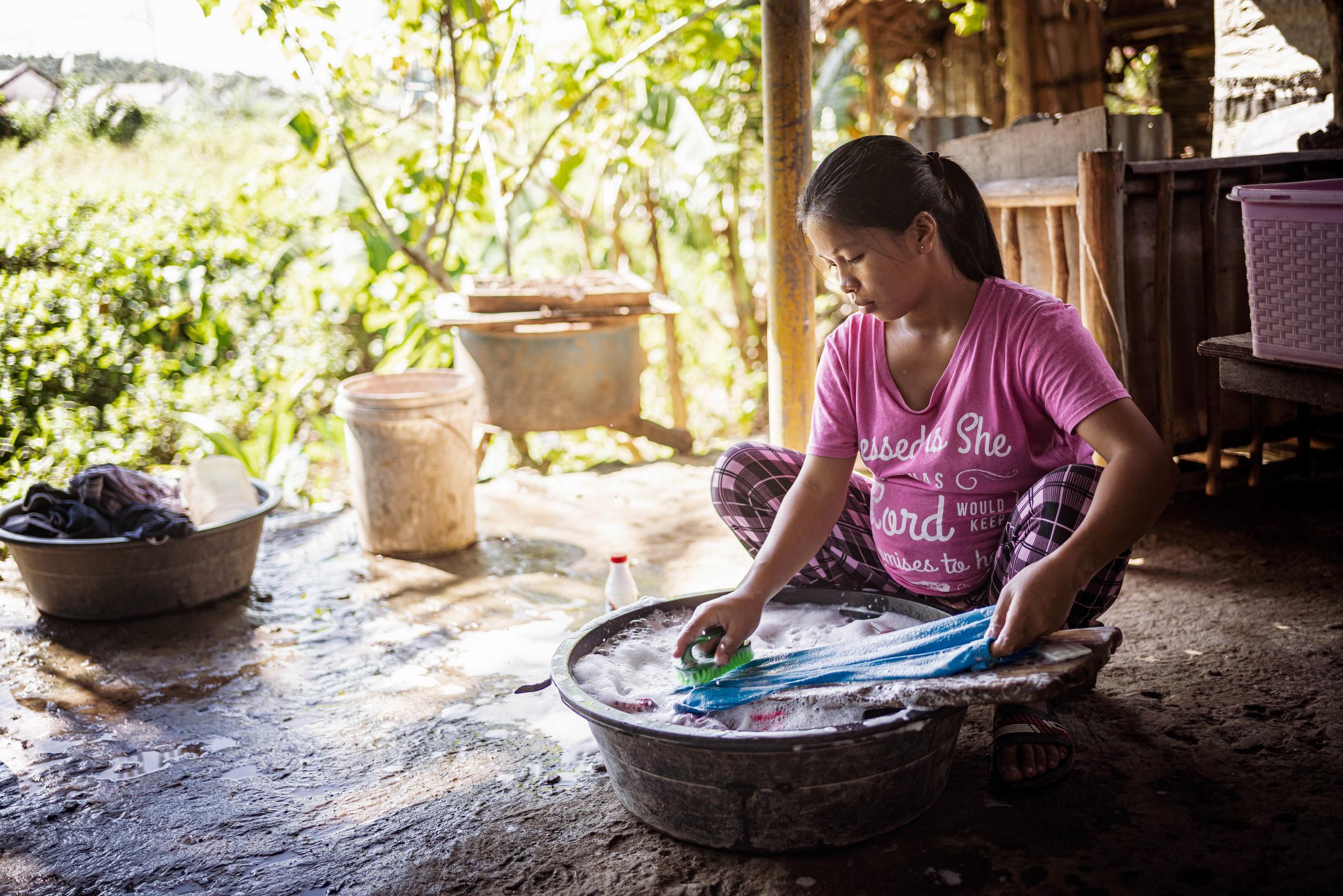 Ein schwangeres Mädchen sitzt auf dem Boden und wäscht Wäsche in einer Schüssel (Quelle: Jakob Studnar)