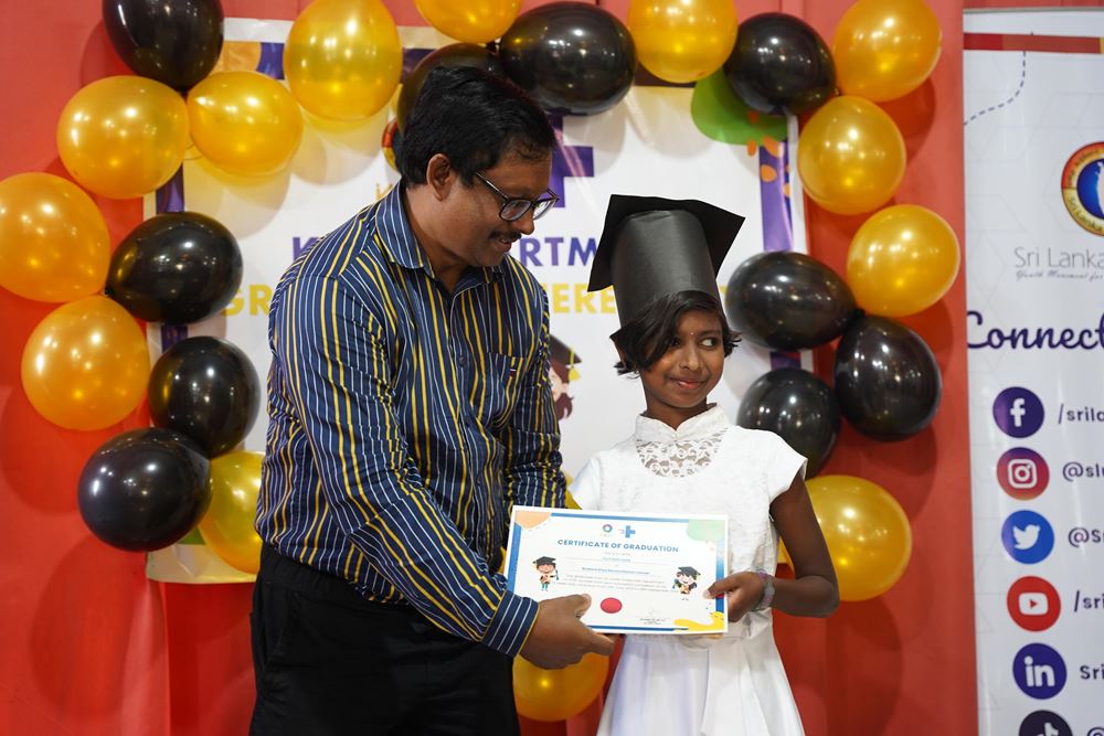 Ein Mann überreicht einem Mädchen eine Urkunde, umrahmt von vielen goldenen und schwarzen Luftballons (Quelle: Christian Nusch) Ein großer Augenblick im Leben der Kinder: die Überreichung der Abschlussurkunden (Foto: Christian Nusch)