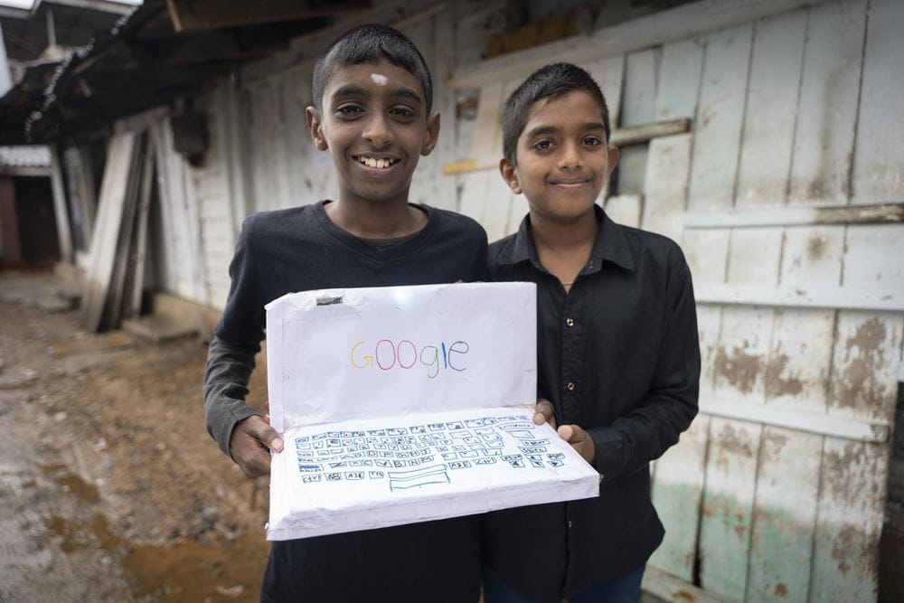 Zwei Jungen zeigen einen aus Papier gebastelten Laptop (Quelle: Christian Nusch) Kajan und Hakesh haben einen Laptop aus Papier gebastelt; wenn man ihn einschaltet, geht sogar ein Licht an! (Foto: Christian Nusch)