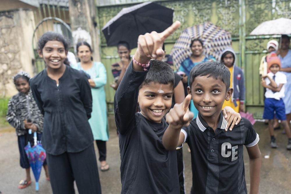 Jungen beim Straßentheater im Regen (Quelle: Christian Nusch) Beim Straßentheater ging es um fehlendes Wasser: Erst beschuldigten sich die beiden Familien unterschiedlicher Religionen gegenseitig, dann reparierten sie die Wasserleitung gemeinsam (Foto: Christian Nusch)