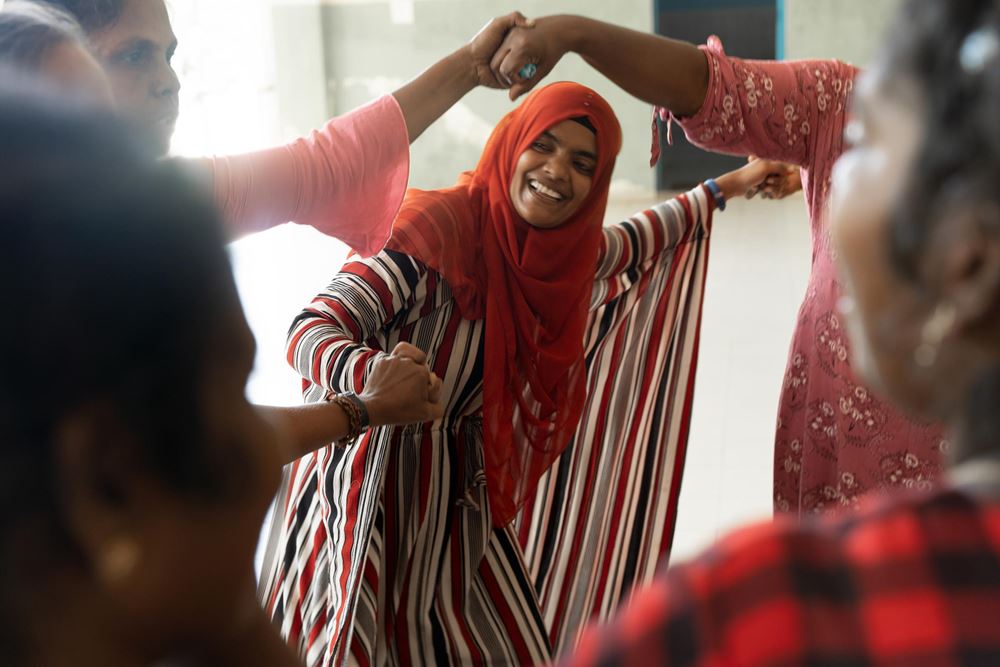 Konfliktlösungsworkshop: Eine Frau hält lachen die Hände anderer Frauen (Quelle: Christian Nusch) Konfliktlösungsworkshop: Eine Frau hält lachen die Hände anderer Frauen (Quelle: Christian Nusch)