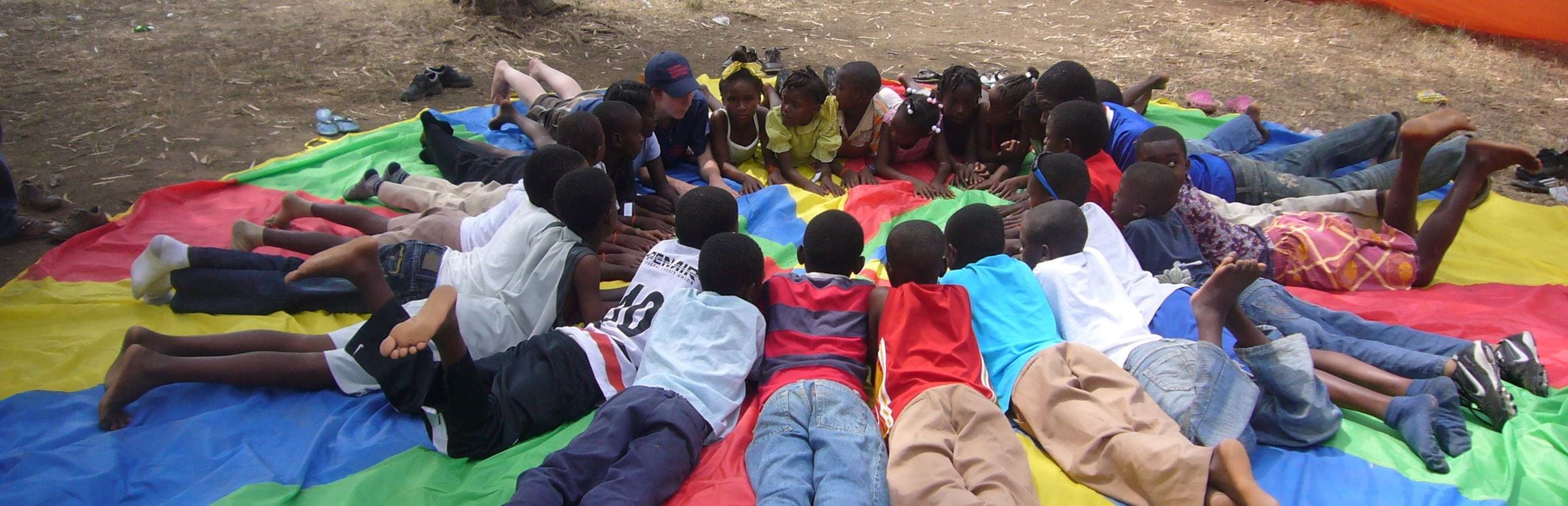 Kinder in Haiti liegen im Kreis bäuchlings auf einer bunten Decke. (Quelle: Kristina Manz)