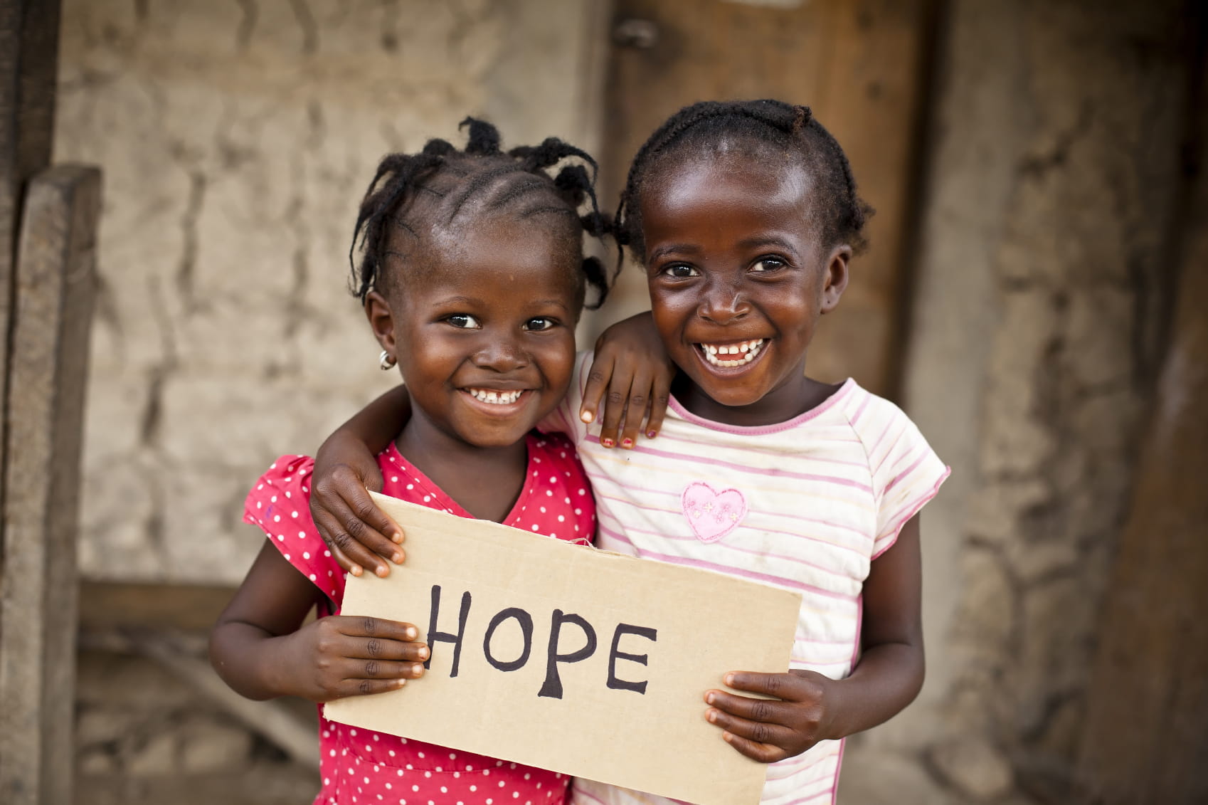 Zwei Mädchen halten ein Schild mit der Aufschrift "HOPE". (Quelle: MShep2 / © iStockphoto)