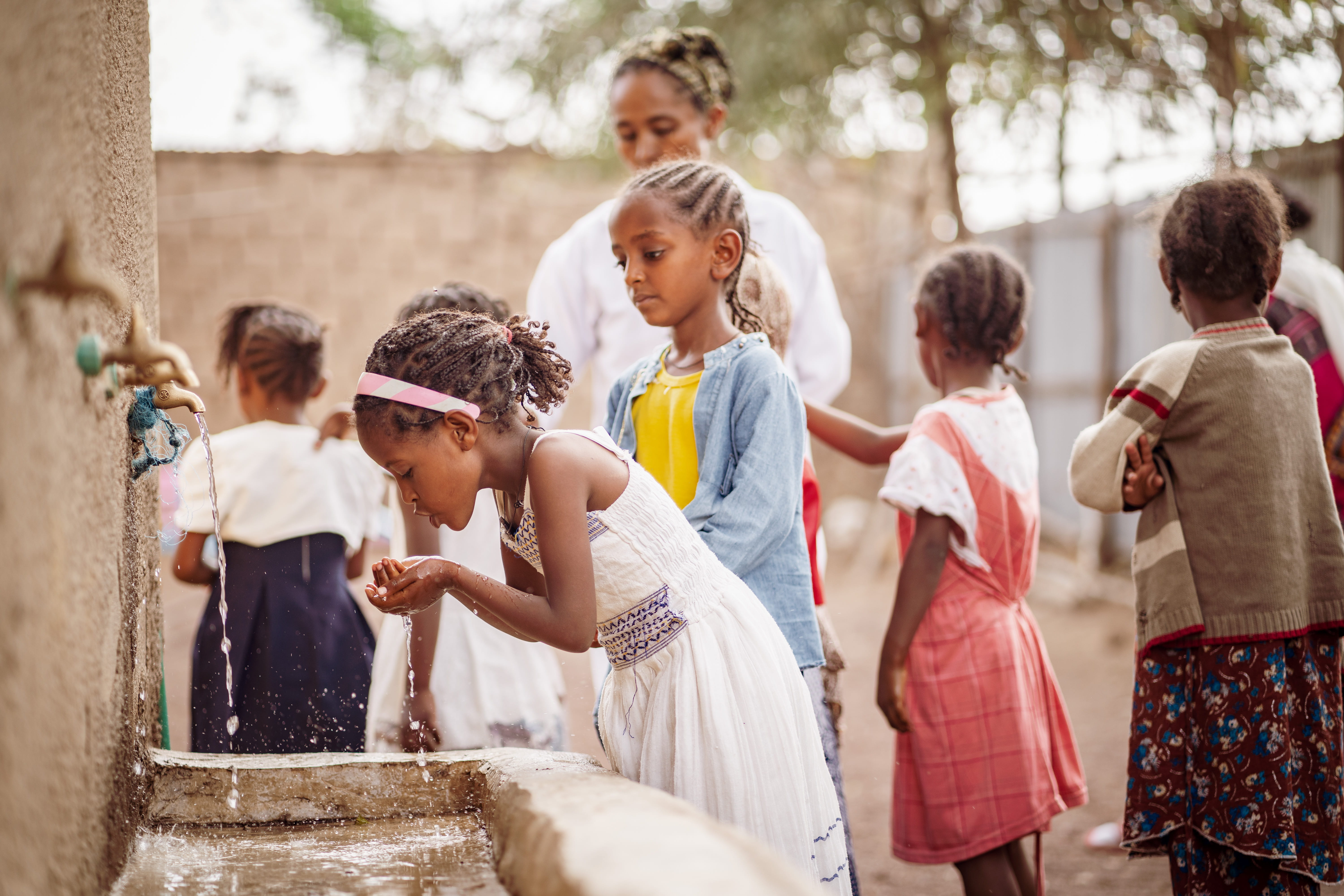 Ein äthiopisches Mädchen beugt sich über ein Waschbecken und trinkt sauberes Wasser. (Quelle: Jakob Studnar)