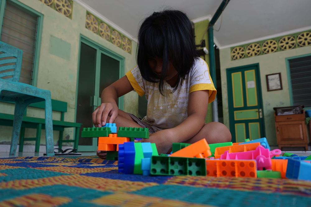 Ein Mädchen aus Indonesien sitzt auf dem Boden und spielt mit buntem Spielzeug. (Quelle: Christiane Dase) Ein Mädchen aus Indonesien sitzt auf dem Boden und spielt mit buntem Spielzeug. (Quelle: Christiane Dase)