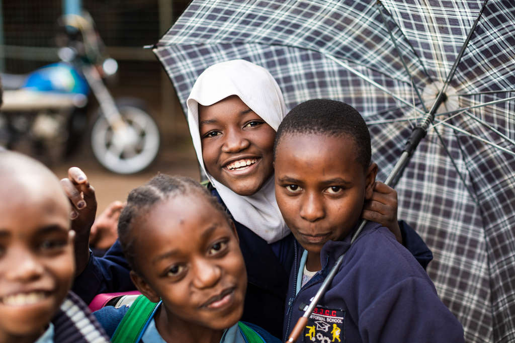 Eine Kindergruppe steht lachend unter einem Schirm. (Quelle: Lars Heidrich)