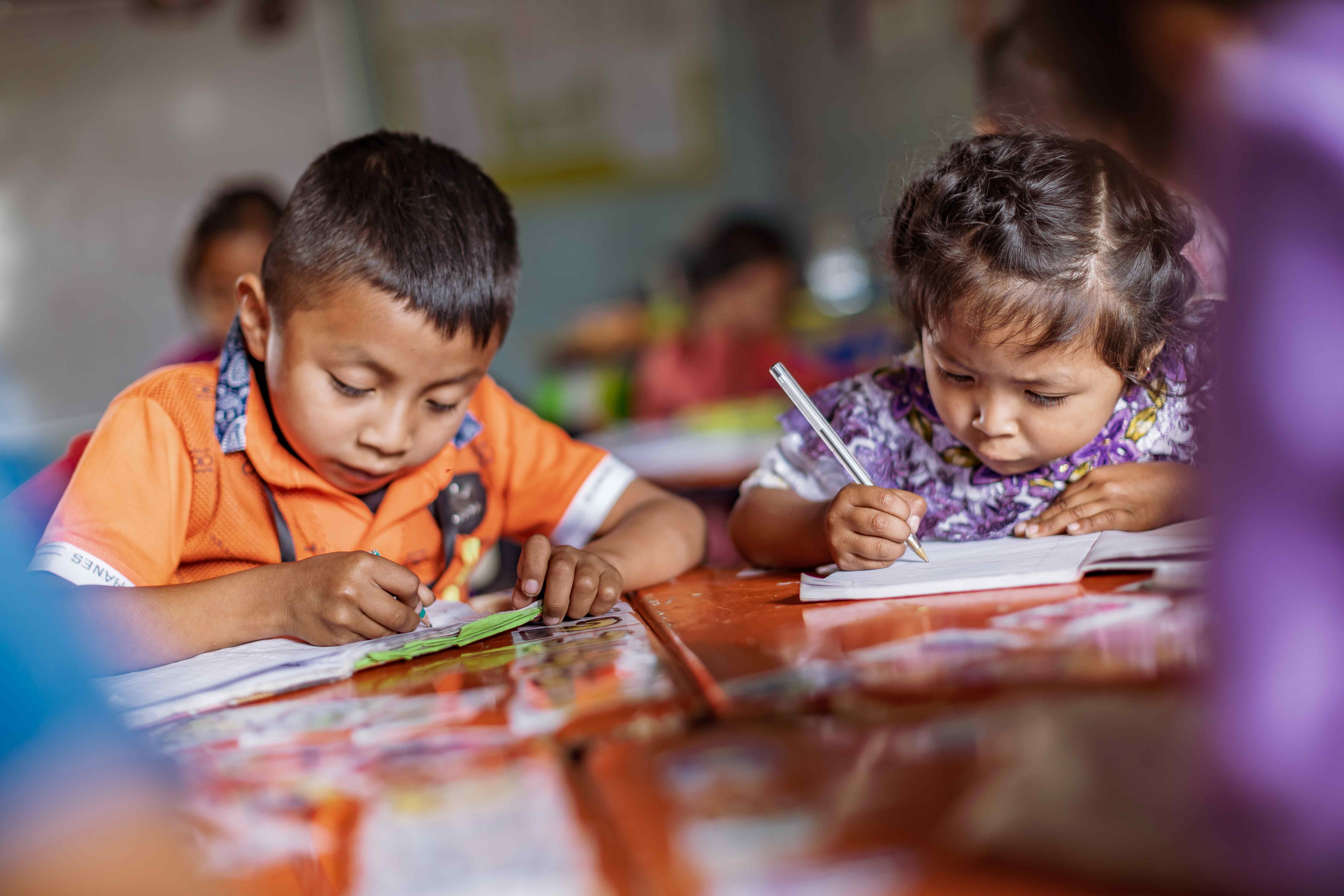 Zwei Vorschulkinder aus Guatemala beugen sich konzentriert über ihre Schreibhefte. (Quelle: Jakob Studnar)
